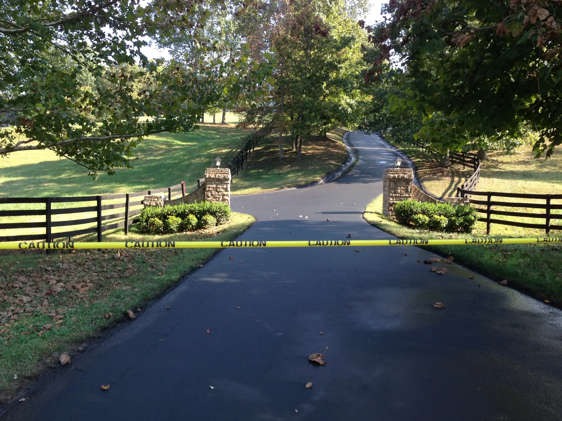 Fresh asphalt drive through a stone-pillar gated entrance